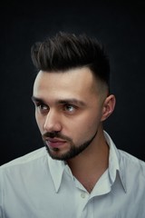 Obraz premium Portrait of handsome young man against studio background. Perfect hairstyle, modern stylish haircut. Attractive guy with fashion hairstyle. Confident man with short beard. Barbershop concept.