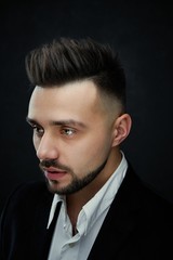 Portrait of handsome young man against studio background. Perfect hairstyle, modern stylish haircut. Attractive guy with fashion hairstyle. Confident man with short beard. Barbershop concept.