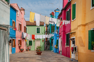 Fototapeta na wymiar Typical colorful houses and airing linen in the street in Burano island, Venice, Italy