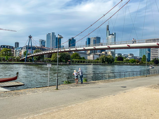 Frankfurt, Germany - 08th May 2020: A german photographer visiting the city, taking pictures of the promenade at the river Main with the Holbeinsteg pedestrian bridge and the skyline in the background