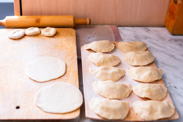 cooking dumplings with potatoes, on a wooden board a preparation of dough, on another board a finished product, Russian cuisine