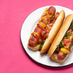 Hot dog with pico de gallo salad on pink background