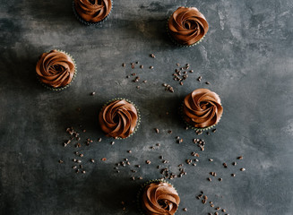 Dark chocolate cupcakes and cocoa nibs on dark background. Sweet food concept. 