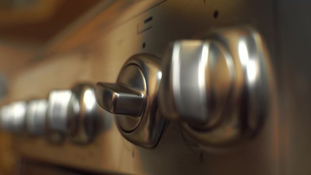 hand twist knob on modern gas stove. Woman turn temperature on oven button.