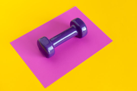 violet dumbbell on a pink background on a yellow background