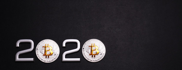 Date 2020 with Bitcoin on black textured background.