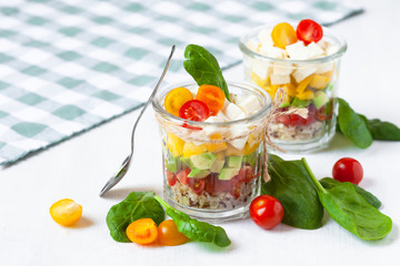 Concept of healthy food, clean eating, low calories delicious meal. Salad with quinoa and fresh vegetables with olive oil in glass jar.  Zero waste no plastic. Close up white background copy space