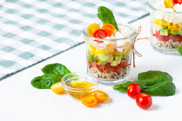 Concept of healthy food, clean eating, low calories delicious meal. Salad with quinoa and fresh vegetables with olive oil in glass jar.  Zero waste no plastic. Close up white background copy space