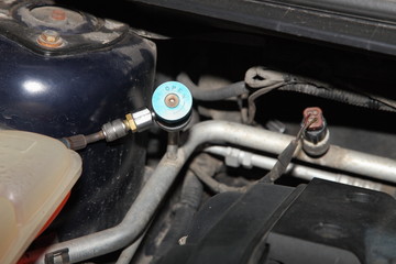 Obraz premium Car A/C blue low pressure valve on sensor in big pipe engine compartment of the car, vehicle air conditioner vacuuming, repair service and refilling