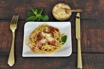 spaghetti boiled with tomato sauce and parmesan cheese, a fork and a golden knife