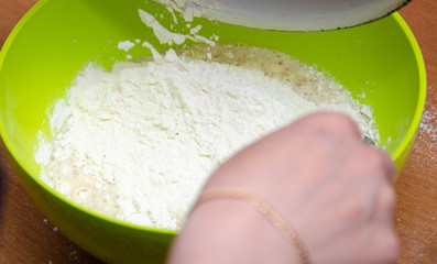 A female hand pours flour into a bowl with yeast and water and sugar. Making pizza  dough