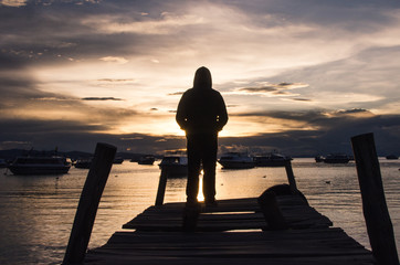 Silueta de persona de espaldas contemplando el atardecer junto al mar en Copacabana, Bolivia