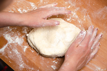 Fototapeta premium Female hands knead, knead the pizza dough. Dough, flour, cook, pizza. Girl rolls rolling pin dough