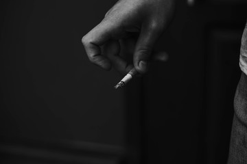 the man is holding a cigarette in his hand. black and white photo