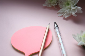 Pens, stickers and flowers on a pink background
