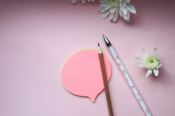 Pens, stickers and flowers on a pink background