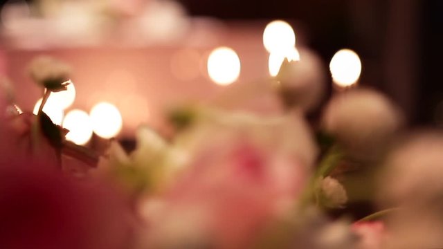 Long white candles burning in candelabrums. Candle lights reflect on pink grand piano surface in romantic atmosphere. Fresh flowers in bouquet composition for date evening. Valentines day decoration.