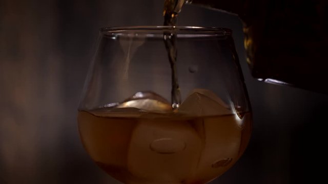 pouring whiskey into a glass with ice cubes