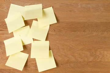 Sticky notes. Blank yellow square paper stickers on natural wooden board background