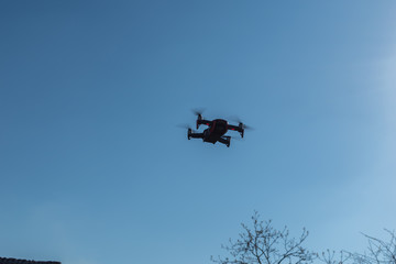 Small sized red drone with high resolution camera hovering in air for aerial photography.