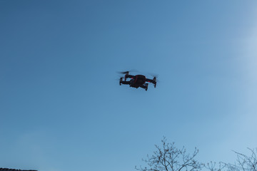 Small sized red drone with high resolution camera hovering in air for aerial photography.