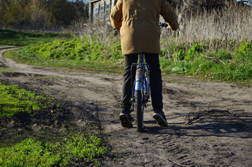 Boy on a bike stands on the middle of a rural road rest spring nature