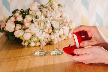 Marriage proposal. Man gives ring with diamond to woman proposing marriage. Indoors restaurant or home, romantic dinner