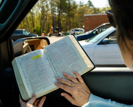 Woman Reading Bible In Car At Drive In Church During COVID Restrictions.