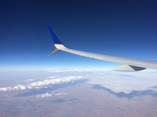 Wing of an airplane flying above clouds and the great plains