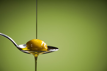 olive oil and green olive on spoon