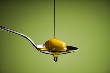 olive oil and green olive on spoon