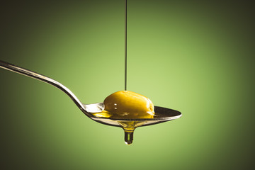 olive oil and green olive on spoon	