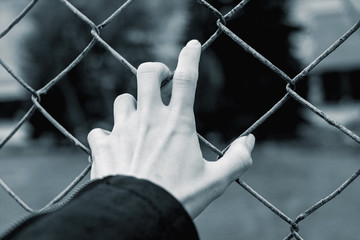 Hand on a fence net in black and white