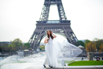 Obraz premium Beautiful bride in rich wedding dress whirls on the square before the Eiffel Tower