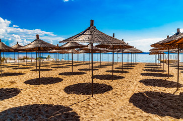 Empty beach with reed beach umbrellas, nobody on the beach. Beautiful blue sky, hot weather. Beach with no travellers and tourists. Cancellations due to coronavirus covid-19. Quarantine.