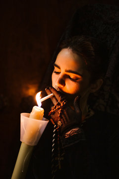 Beautiful woman made up in traditional costume for la semana santa, lighting cigarette on burning candle