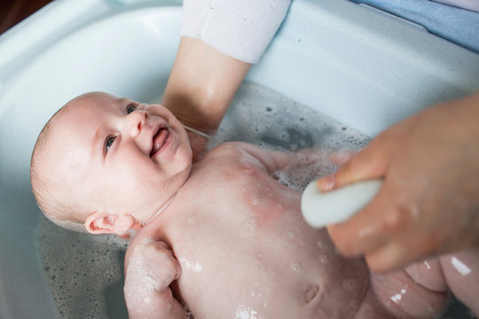 Mother bathing her baby boy in a tub