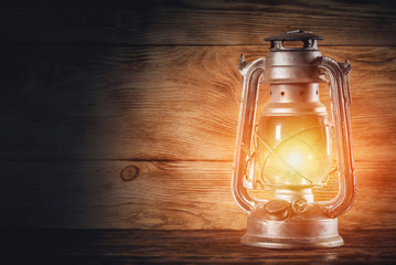 Old magic kerosene lamp on the table on wooden wall background with copy space.