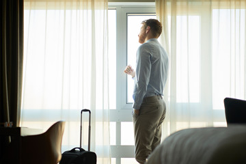 Businessman in hotel room looking out of window