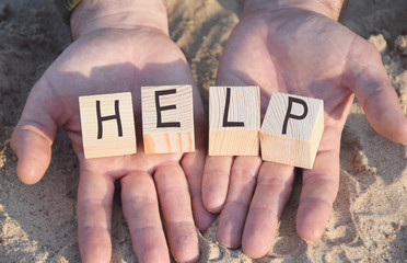 wooden cubes with the inscription help, located on the hands of a person, men, slightly distorted...