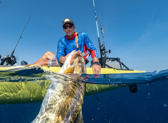 Split shot of man in a kayak catching a fish