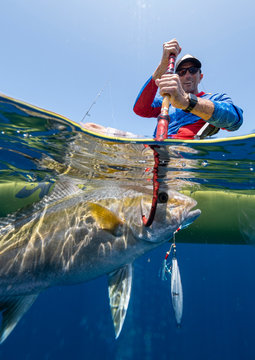 Split shot of happy man in a kayak catching a fish