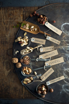 Collection of various nuts with name tags lying on rustic baking sheet
