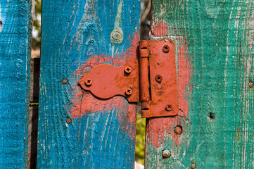 Rusty hinge on a painted timber fence