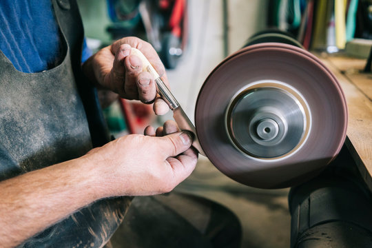 Craftsman making knives in his workshop sharpening the blade