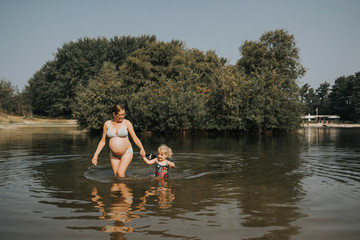 Netherlands, Schiermonnikoog, pregnant mother with daughter in a lake