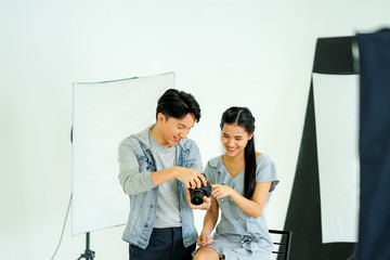 Fototapeta premium Backstage behind the scene of the photo session: the photographer using digital camera taking picture of the female model in the creative home studio work from home during virus pandemic