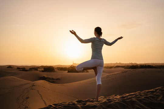 Woman practicing yoga in sand dunes at sunset, Gran Canaria, Spain