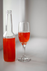 bottle and glass with red cocktail 
