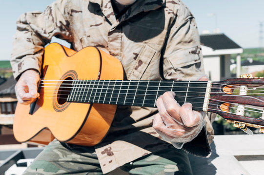 Soldier playing the guitar, with protective gloves